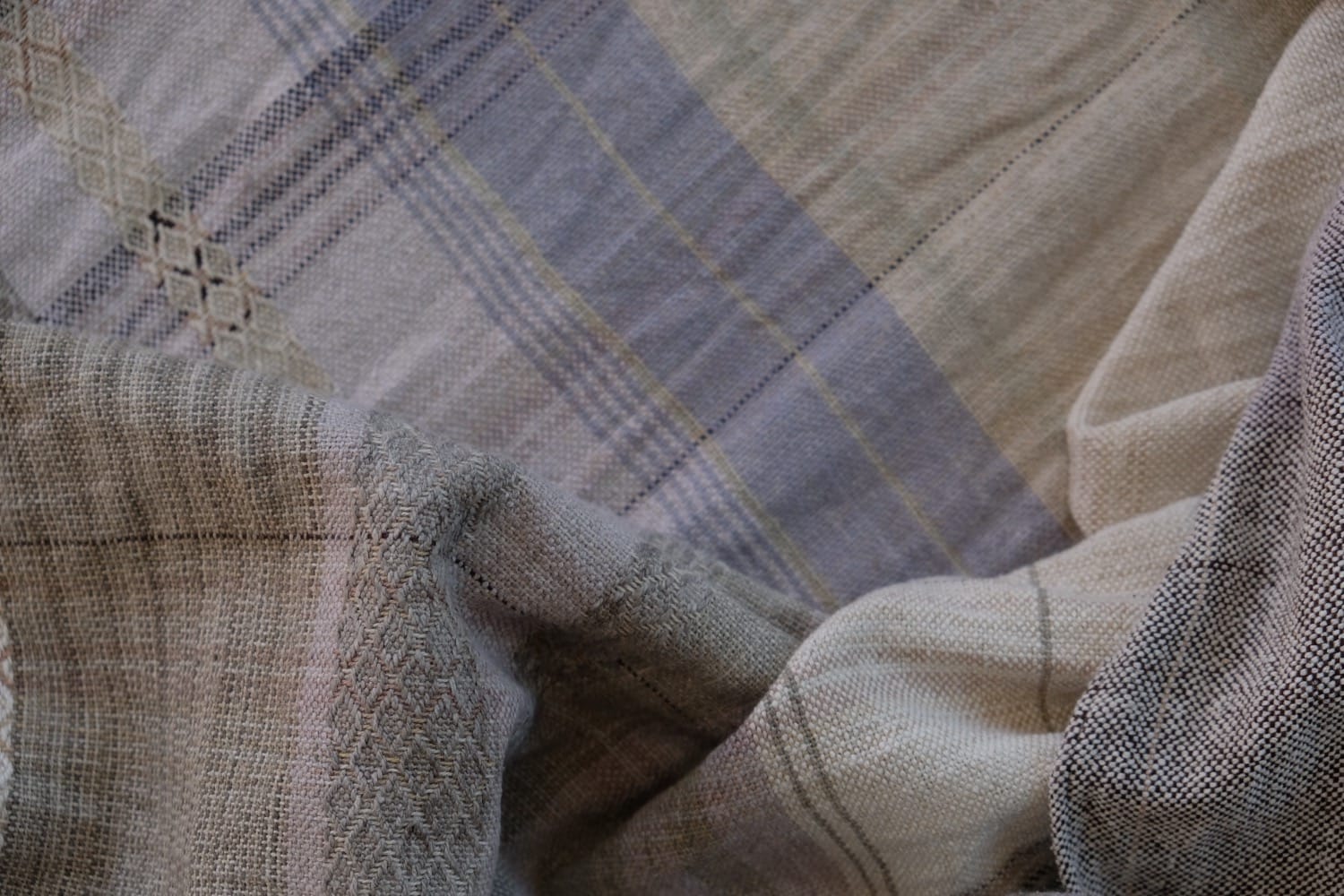 A detail of naturally dyed handwoven fabric in moody shades of gray, misty blue and black with a white moon in the middle and cloud designs throughout