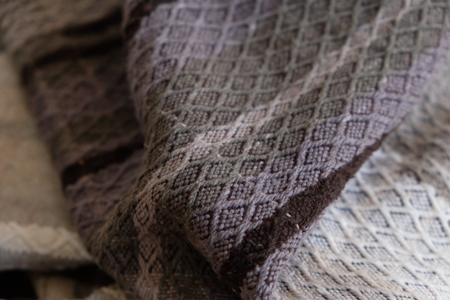 A detail of naturally dyed handwoven fabric in moody shades of gray, misty blue and black with a white moon in the middle and cloud designs throughout