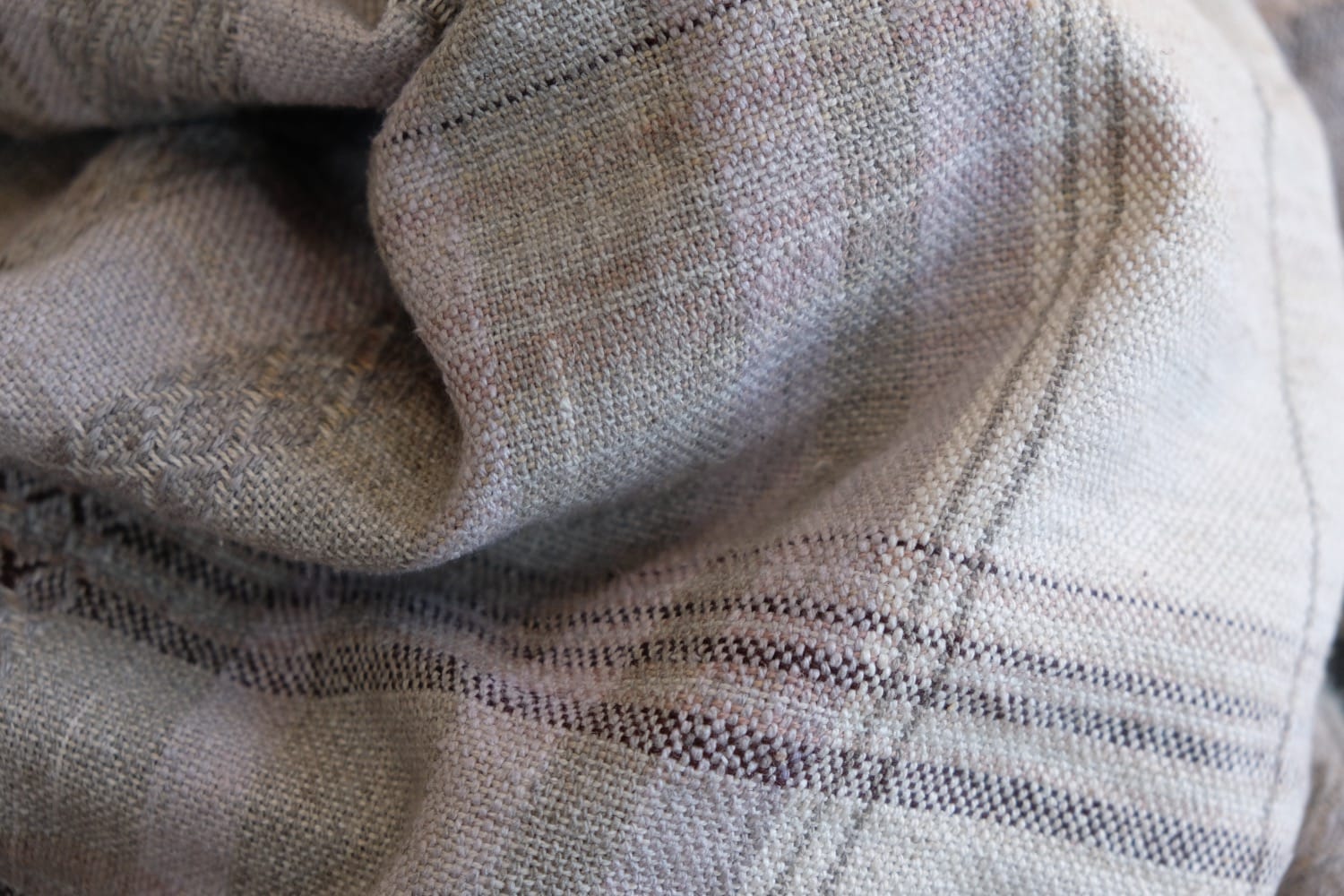 A detail of naturally dyed handwoven fabric in moody shades of gray, misty blue and black with a white moon in the middle and cloud designs throughout