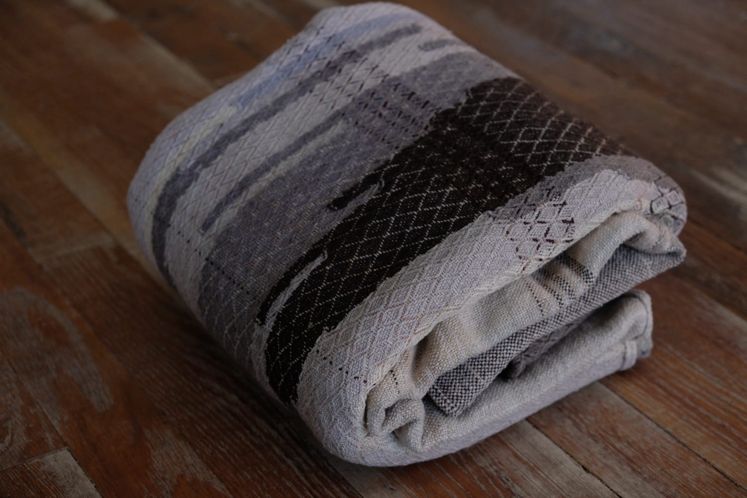 A detail of naturally dyed handwoven fabric in moody shades of gray, misty blue and black with a white moon in the middle and cloud designs throughout