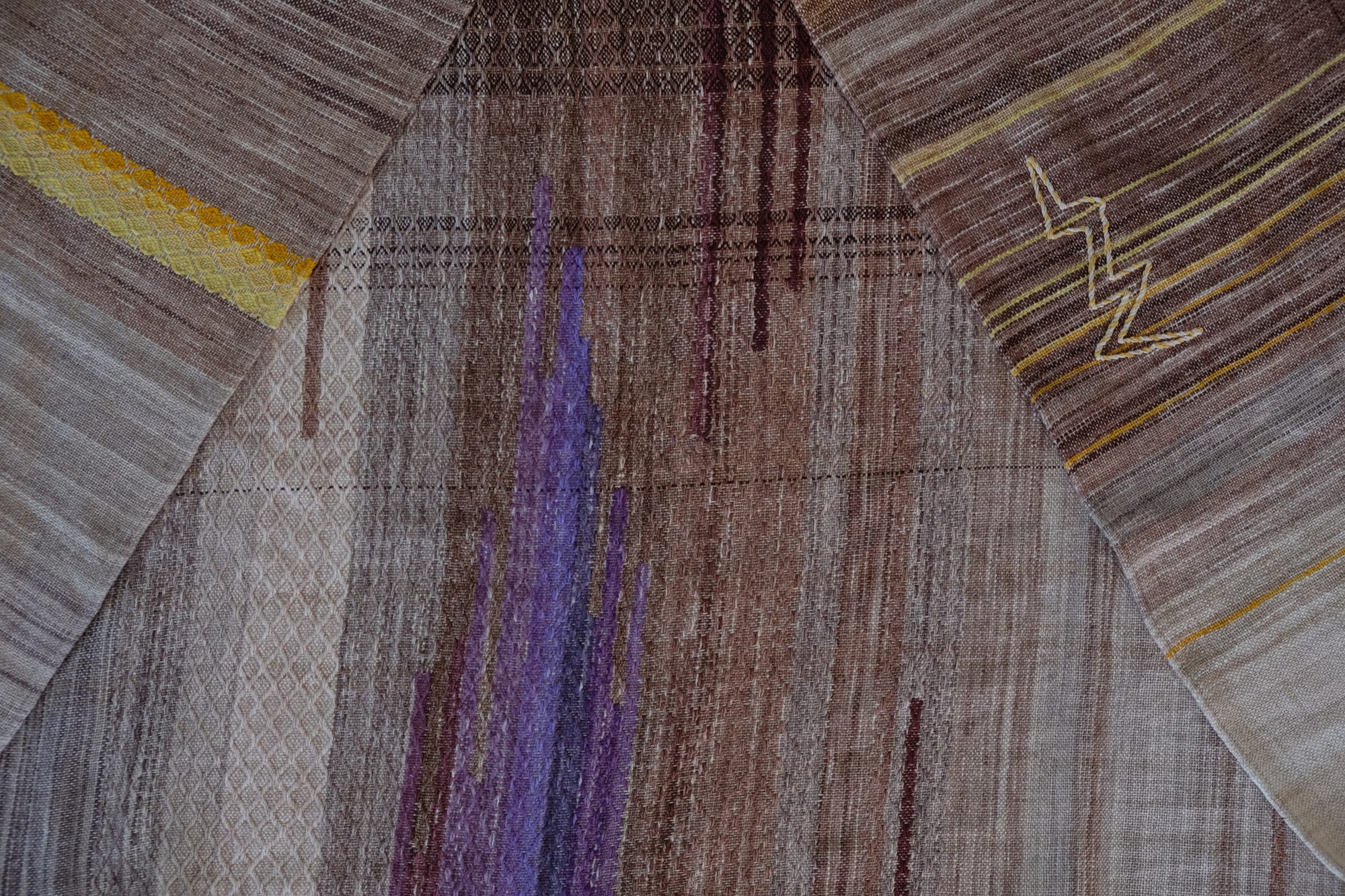 A handwoven shawl with hand dyed raw silk in grey, brown, yellow, purple and red with a lightning bolt detail