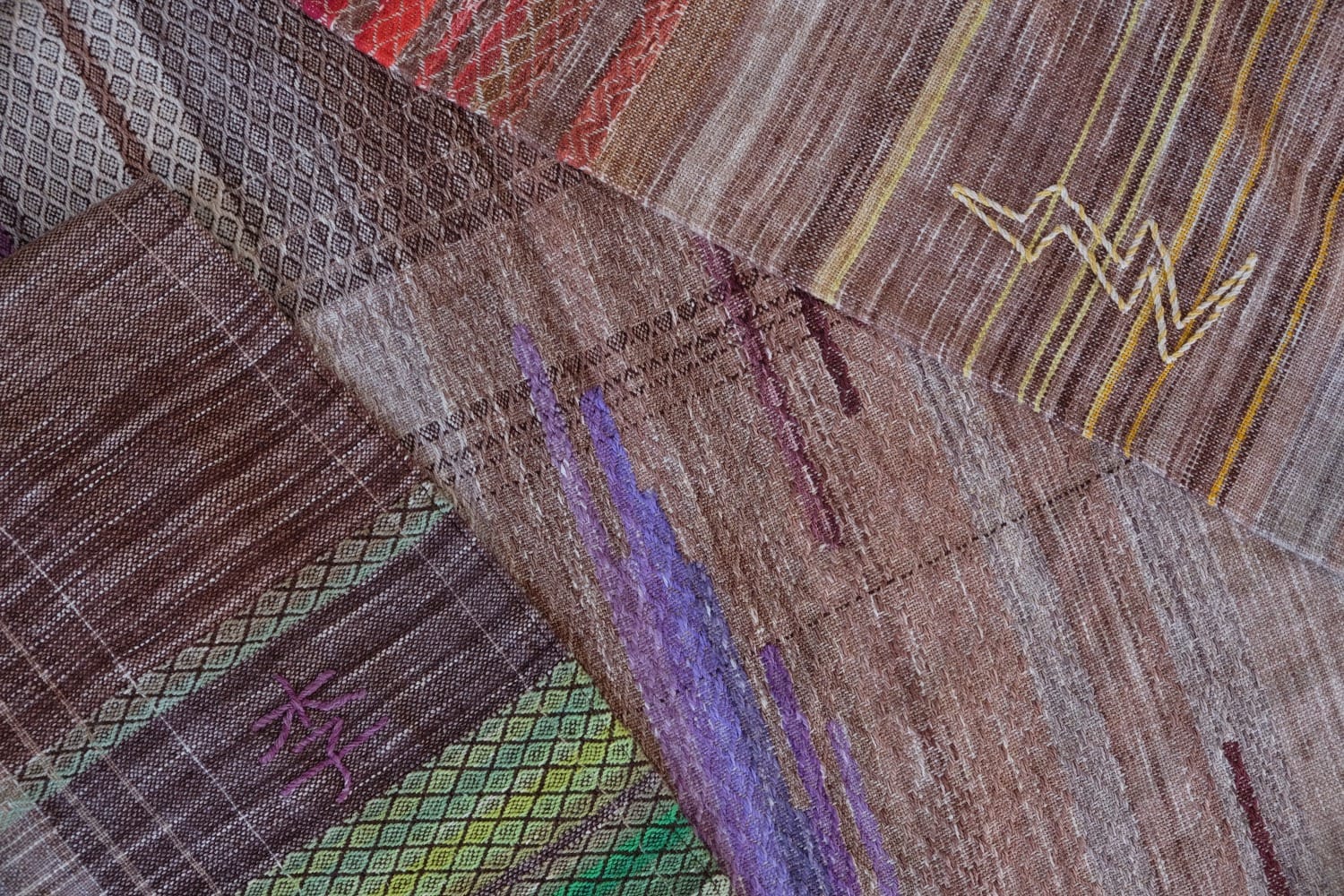 A handwoven shawl with hand dyed raw silk in grey, brown, yellow, purple and red with a lightning bolt detail
