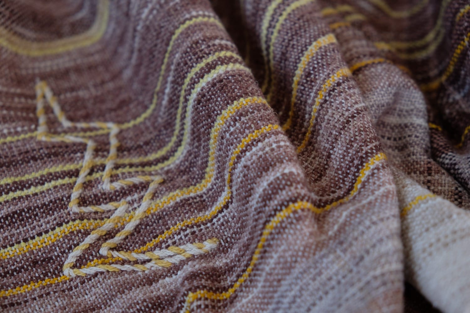 A handwoven shawl with hand dyed raw silk in grey, brown, yellow, purple and red with a lightning bolt detail
