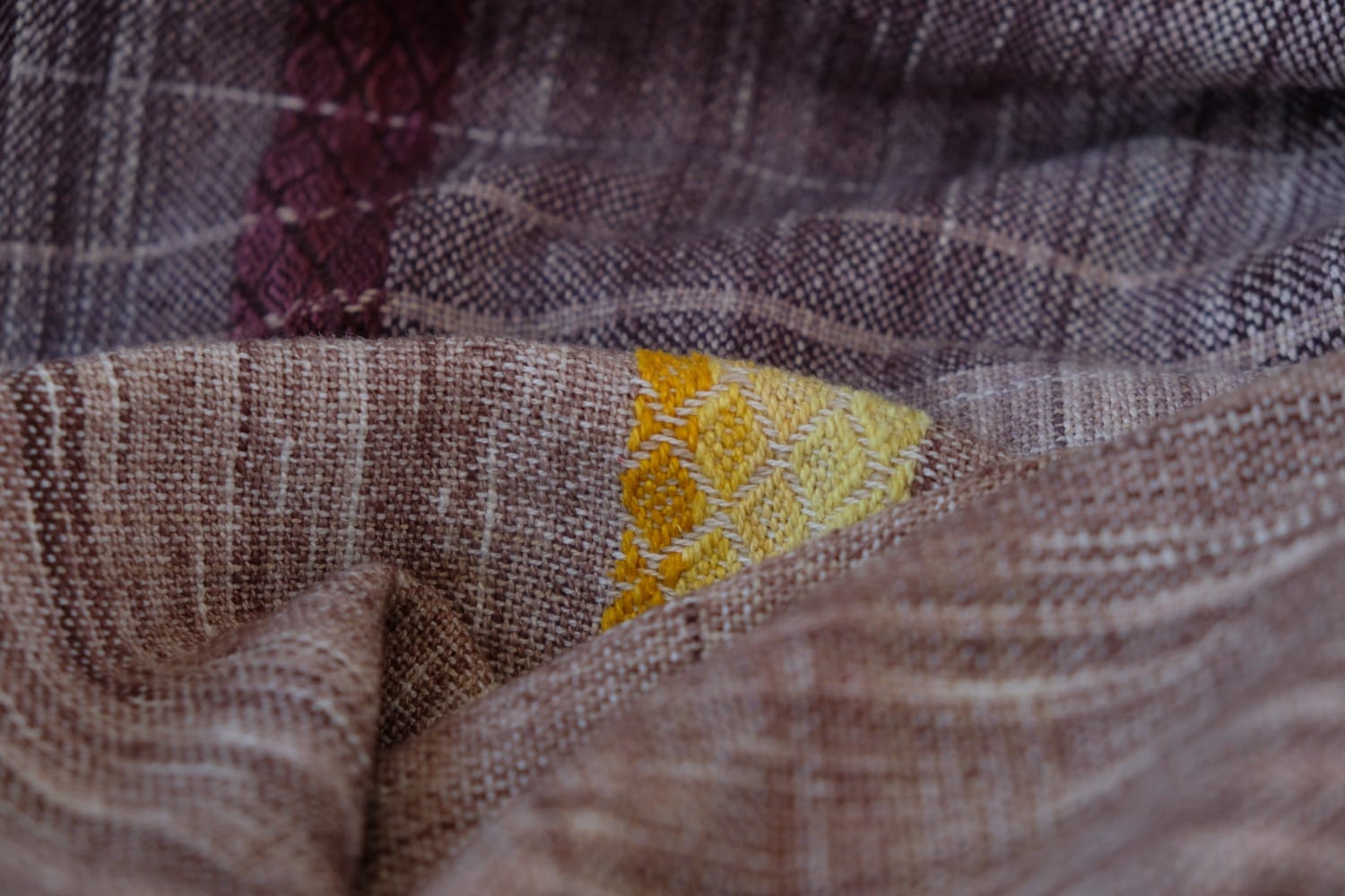 A handwoven shawl with hand dyed raw silk in grey, brown, yellow, purple and red with a lightning bolt detail
