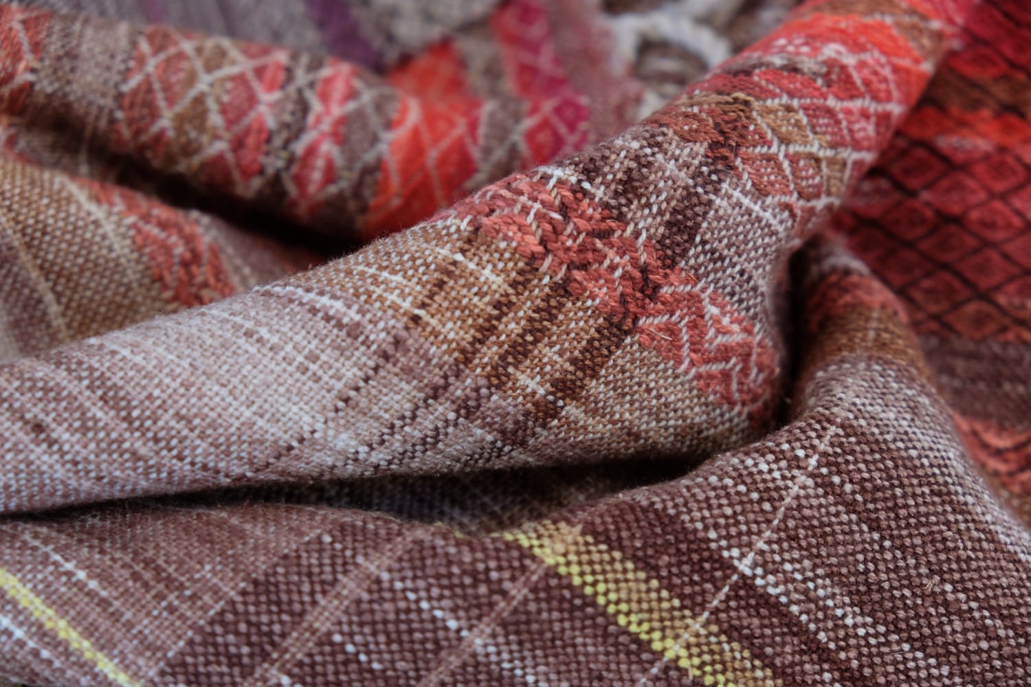 A handwoven shawl with hand dyed raw silk in grey, brown, yellow, purple and red with a lightning bolt detail