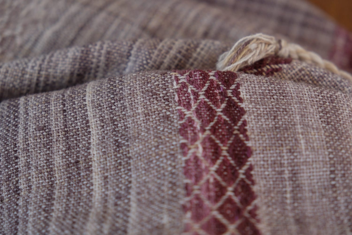 A handwoven shawl with hand dyed raw silk in grey, brown, yellow, purple and red with a lightning bolt detail