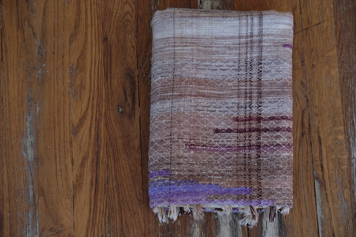 A handwoven shawl with hand dyed raw silk in grey, brown, yellow, purple and red with a lightning bolt detail