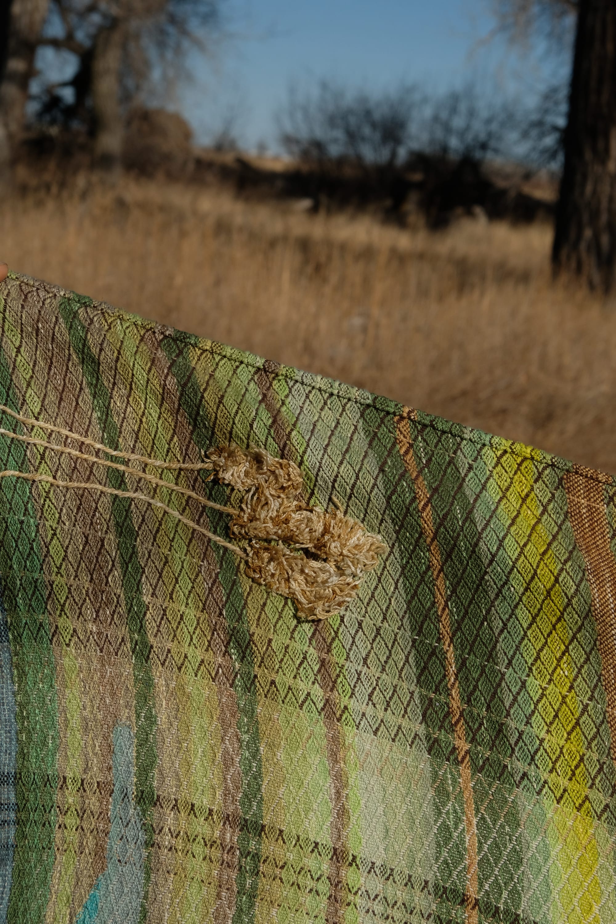 a long length of handwoven fabric in the colors of blue sky, sunrise and dry fields of barley