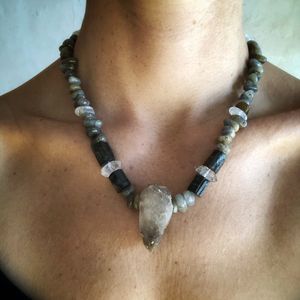 Woman wearing necklace made of drilled stones and crystals in black and gray.