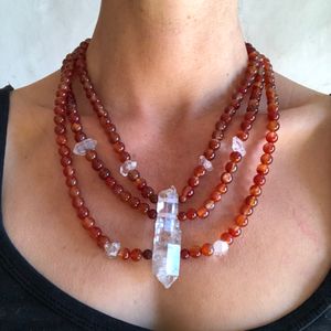 Woman wearing red carnelian stone and clear quartz point necklace