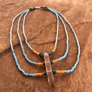 blue yellow and green necklace made with Zambian citrine and antique beads laying flat on a tan stone