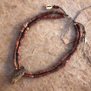 Necklace made of petrified wood and antique red bauxite stone beads laying on a large tan stone 