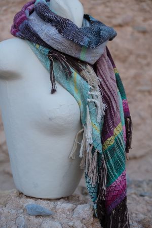 Blue, pink, yellow, purple and teal handwoven silk scarf on a white mannequin.