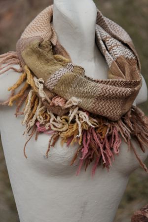 naturally dyed brown, pink, yellow, tan and red merino scarf with fringe on a white mannequin
