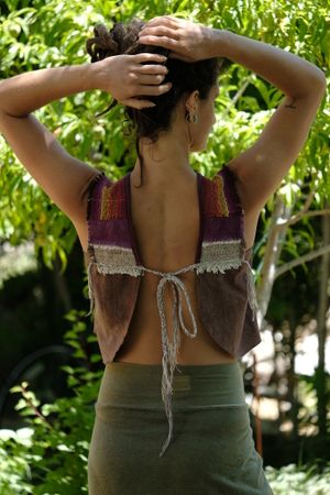 Woman with her back to the camera wearing a green skirt and brown, red, yellow and orange top. 