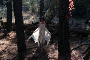 woman wearing white layered silk handmade dress in the forest