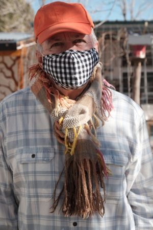Man in an orange baseball cap and flannel shirt wearing handwoven, highly textured cashmere scarf
