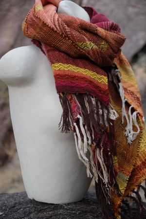 Handwoven red, orange, yellow, brown and white Merino Etherial Scarf on a white mannequin