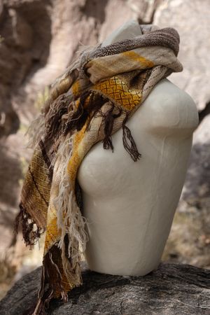 Handwoven raw silk scarf in shades of yellow on a white mannequin