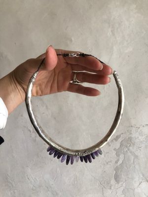 Hand holding silver hoop necklace with purple amethyst spears protruding from the bottom.