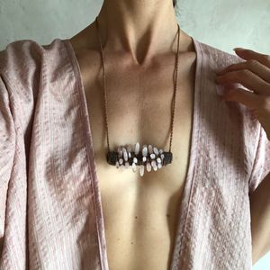 torso of woman wearing pink robe and Freeform knot work tube necklace with rose quartz spears protruding from it 