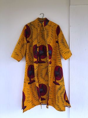 yellow and red fan print hand sewn jacket hanging on a hanger on a white wall