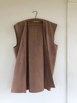 Brown silk vest on a hanger, hanging on a white wall