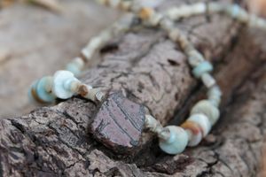 Detail of Tsesit, Afghan Jade and Amazonite adornment resting on a branch