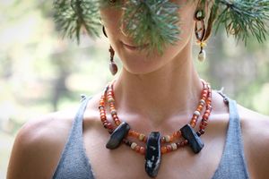 woman wearing dark petrified wood, tan fossilized coral and red orange carnelian necklace