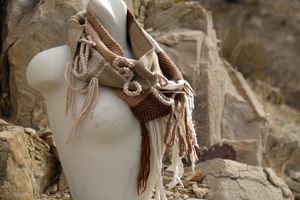 naturally dyed brown, tan, white and green highly fringed and textural infinity scarf on a white mannequin bust in the desert