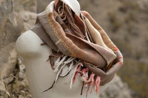 naturally dyed brown, yellow, pink, red and tan fringed infinity scarf on a white mannequin bust in the desert