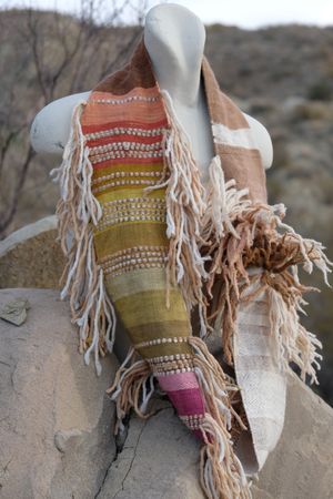 brown, white, pink, salmon, yellow and green highly textured scarf on a white mannequin bust in the desert