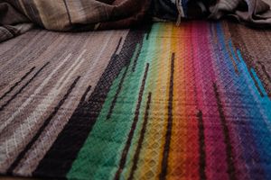 detail of Multi colored handwoven raw silk fabric laying on a wooden floor