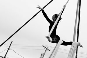 Woman performing aerial silks outside on white fabric