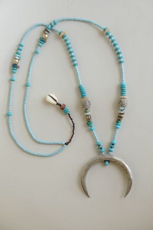 turquoise and blue stone necklace with a silver moon laying on a white backdrop