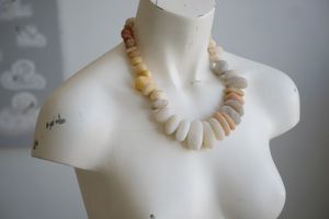 A white colored female formed mannequin wears a short necklace of ocean tumbled stones in pastel colors