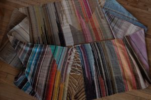 details of geometric shaped, natural and rainbow colored handwoven, diamond pattern fabric on a wooden floor