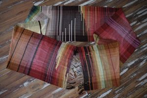 Handwoven diamond pattern fabric in rich shades of fall and earth laying on a wooden floor