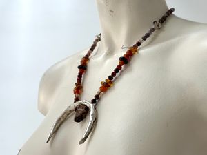 A painted white mannequin wears a necklace with a silver Crescent moon shape And beads of Amber Quartz 