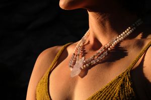 A dramatically lit image of a woman wearing a luminous crystal necklace