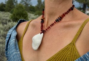 A woman wears a necklace of Marble and Amber wrapped in indigo died shawl